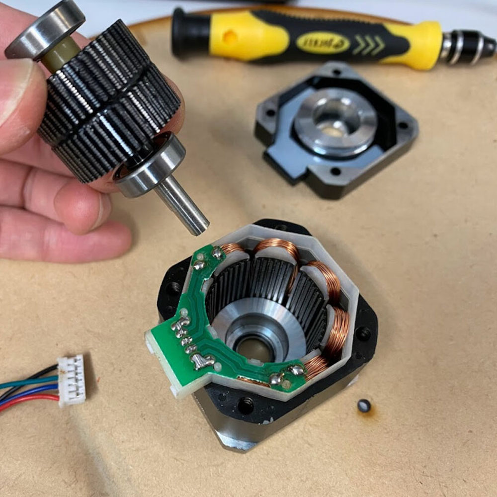 Motor pas cu pas desfăcut, cu rotor, stator și rulmenți vizibili